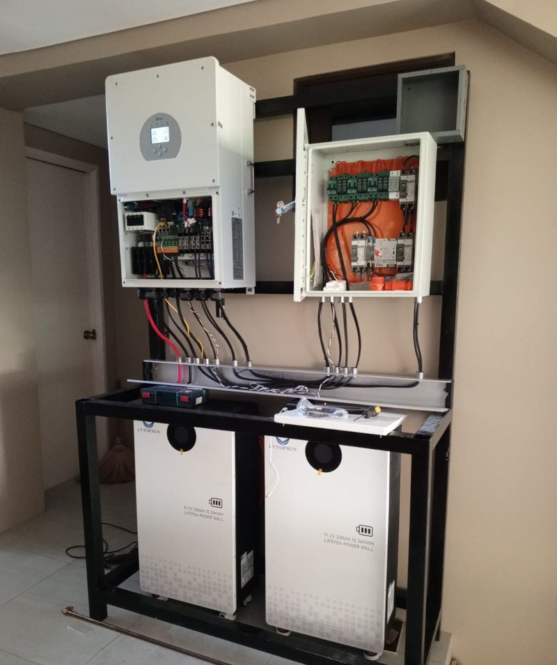A hybrid inverter and protection box on a frame above two large battery units.