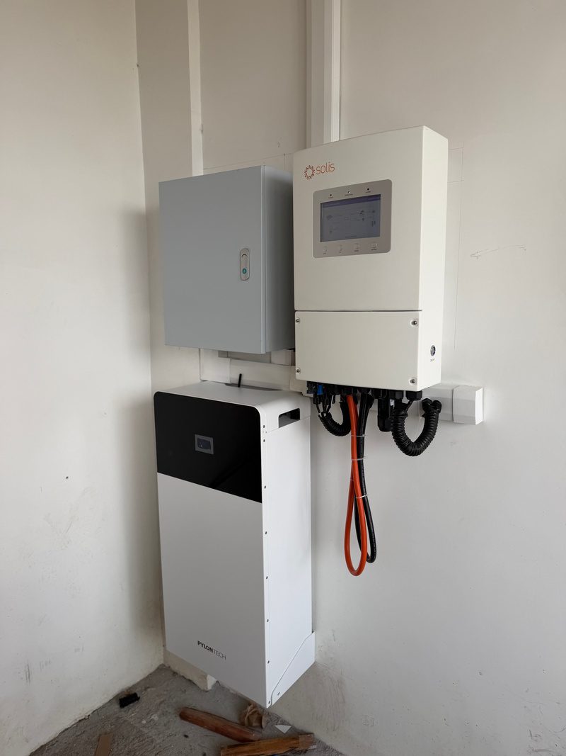 Inverter screen on, protection box to its left, battery underneath, trunking up to the ceiling.