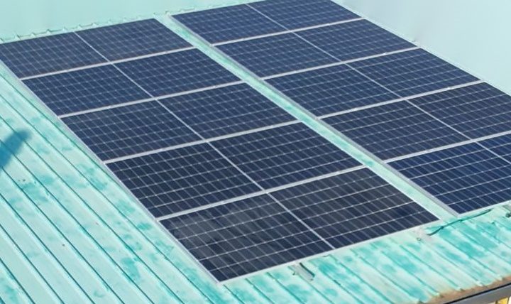 Aerial view of a new panel array in two blocks on a teal metal roof.